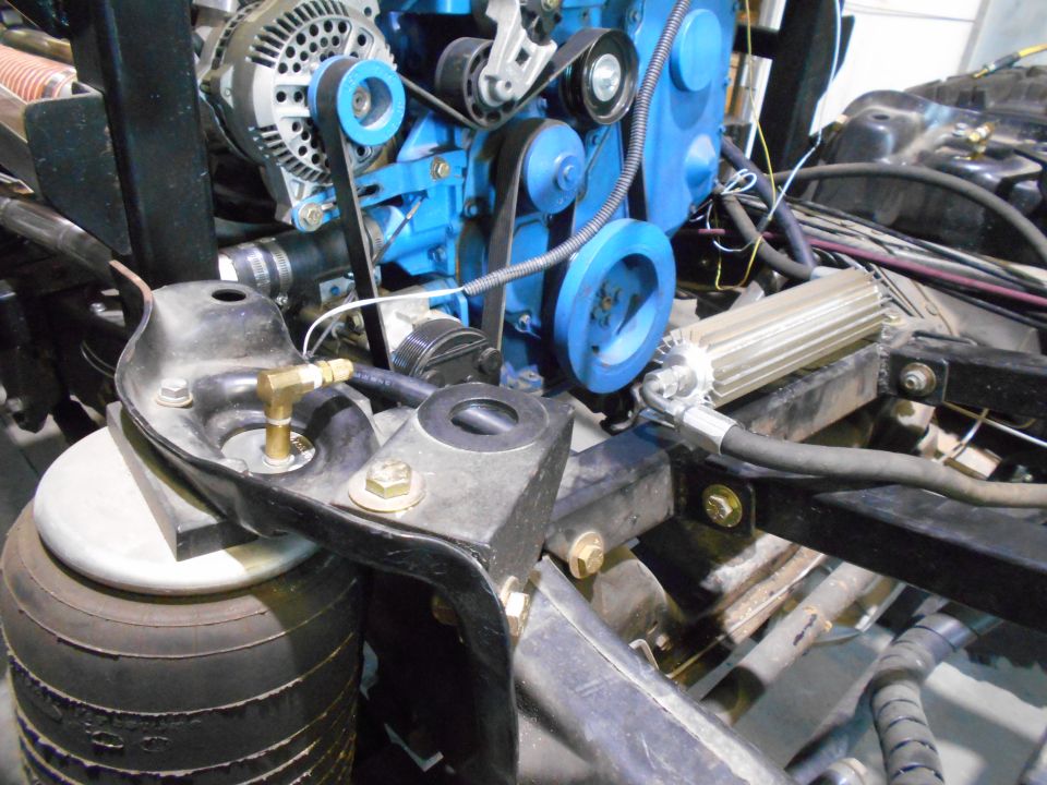 Engine components with blue block, alternator, and belts. Air suspension bag visible