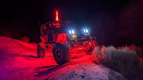 1992 Jeep Wrangler - This heavily modified off-road vehicle is illuminated by custom red and blue lighting during a nighttime excursion.