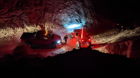 1992 Jeep Wrangler - Off-road vehicles navigate a cave passage at night, illuminated by artificial lights.