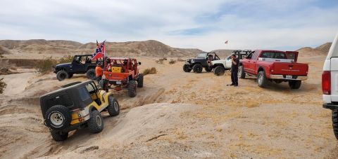 1992 Jeep Wrangler - A group of off-road vehicles, including a yellow Jeep Wrangler, navigate a desert trail.