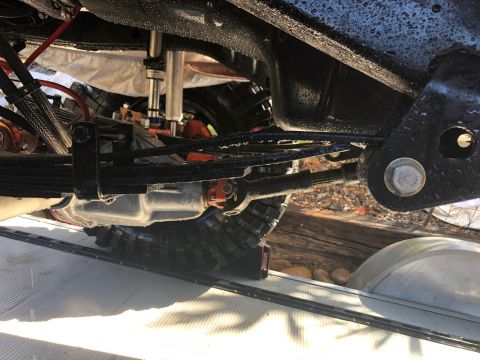 1992 Jeep Wrangler - The underside of a vehicle reveals its suspension and drivetrain components, including leaf springs and a driveshaft.