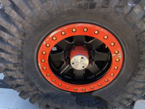 1992 Jeep Wrangler - Detail of an off-road tire and wheel assembly an orange beadlock and spiked lug nuts.