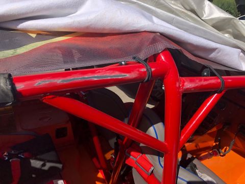1992 Jeep Wrangler - Close-up of a red roll cage partially covered by a white tarp, with visible scuff marks on the tubing.