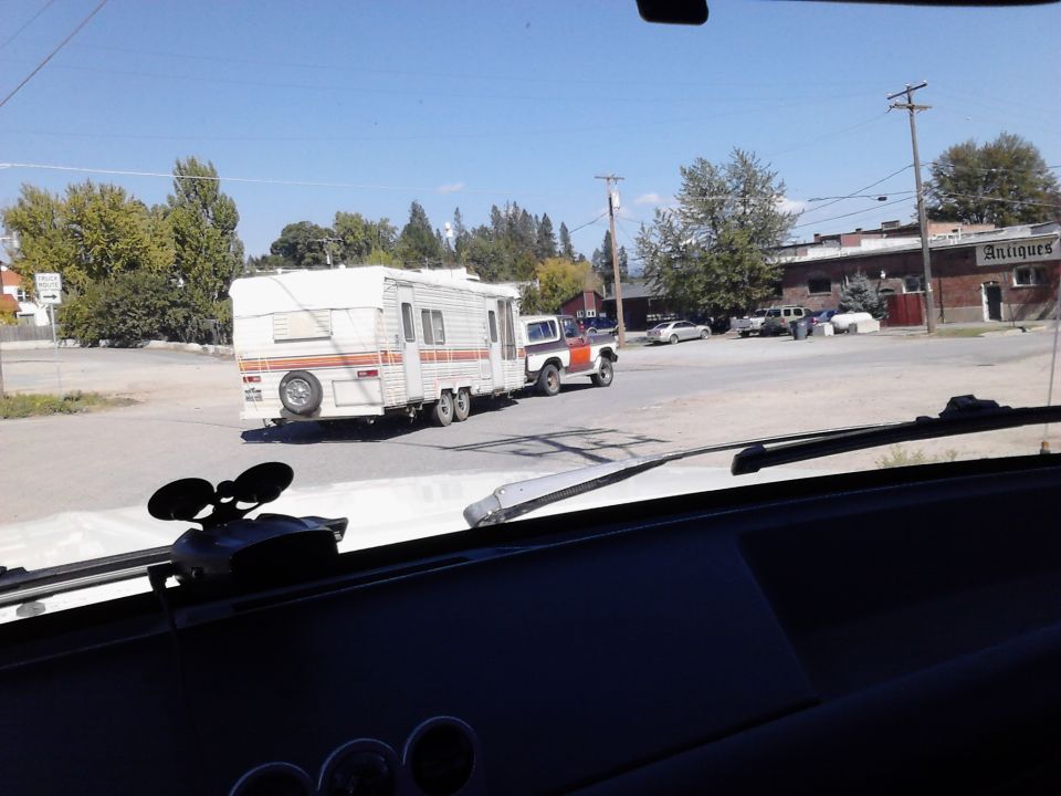 1978 Ford Bronco towing a travel trailer down a street