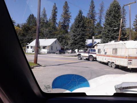 1978 Ford Bronco - A 1978 Ford Bronco tows a trailer past houses and trees on a sunny day.