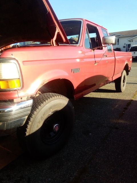 1994 Ford Bronco - This red pickup truck is shown from a 3/4 front angle with its hood open.