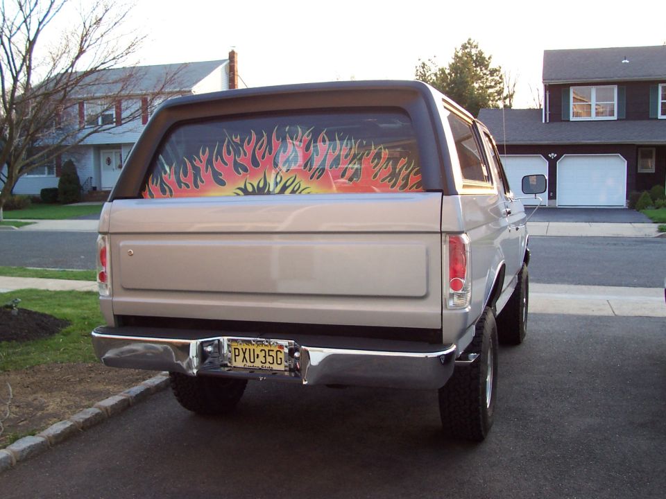 Silver Ford Bronco rear view with flame decal on rear window and license plate PXU-35G