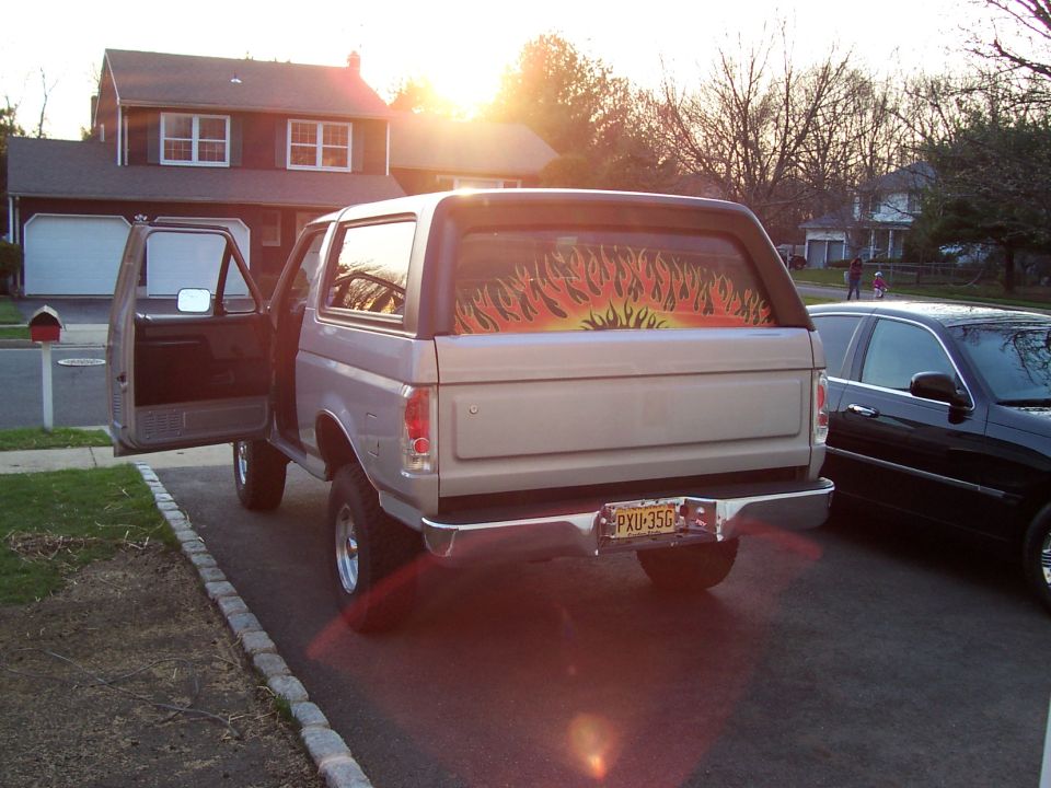 Rear view of a 1990 Ford Bronco with flame decal on window and custom license plate