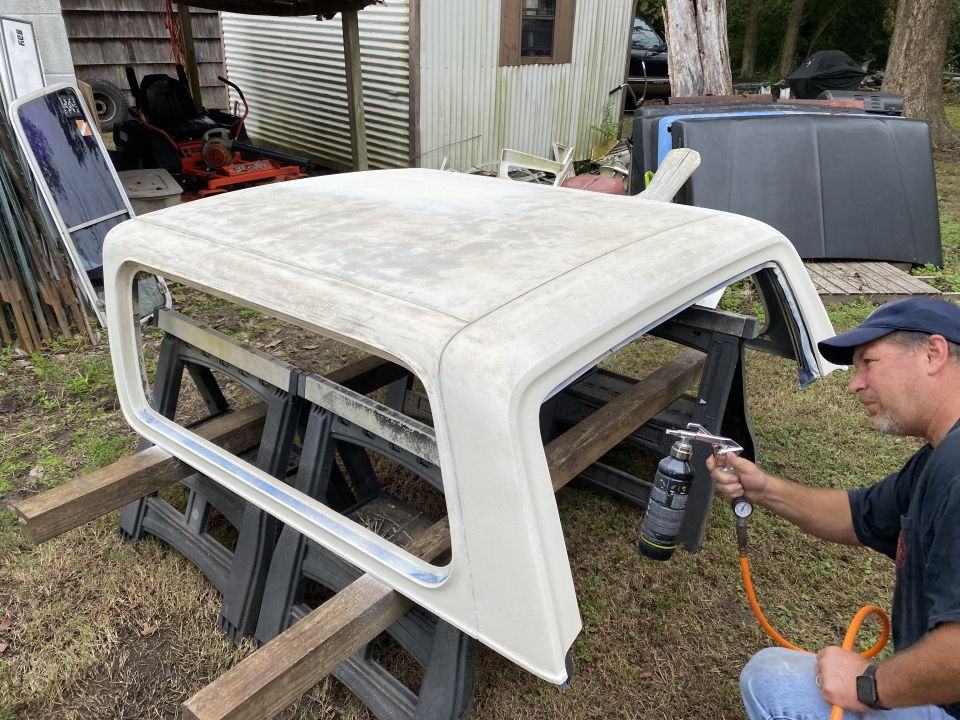 Man spraying a white truck cap with a spray gun