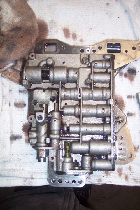 1973 Ford F-250 - This is a close-up overhead view of a transmission valve body, likely removed from a vehicle for service. The metal component is covered in…