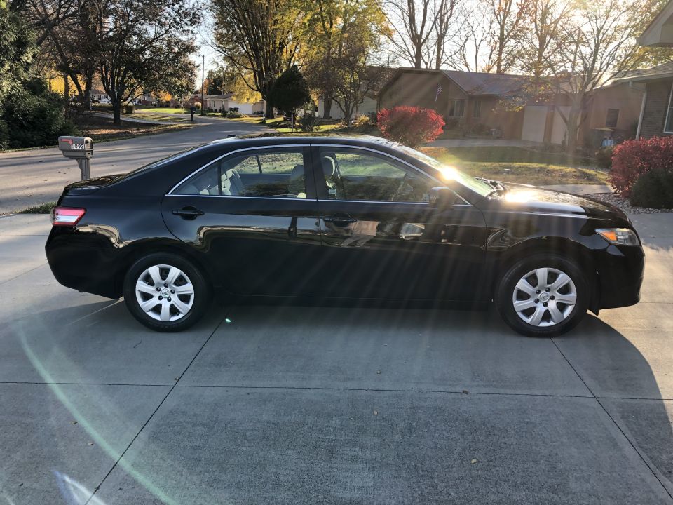 Black 2011 Toyota Camry parked in a driveway, side view.