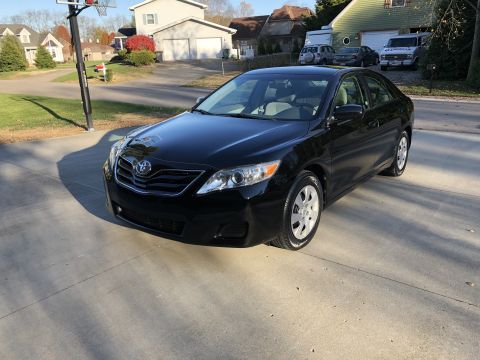 2011 Toyota Camry - A dark sedan is captured in motion, its front quarter visible against a blurred background.