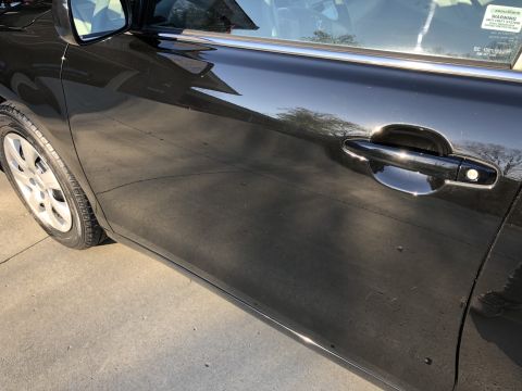 2011 Toyota Camry - Close-up of a black car's side door and wheel, with a warning sticker on the window.