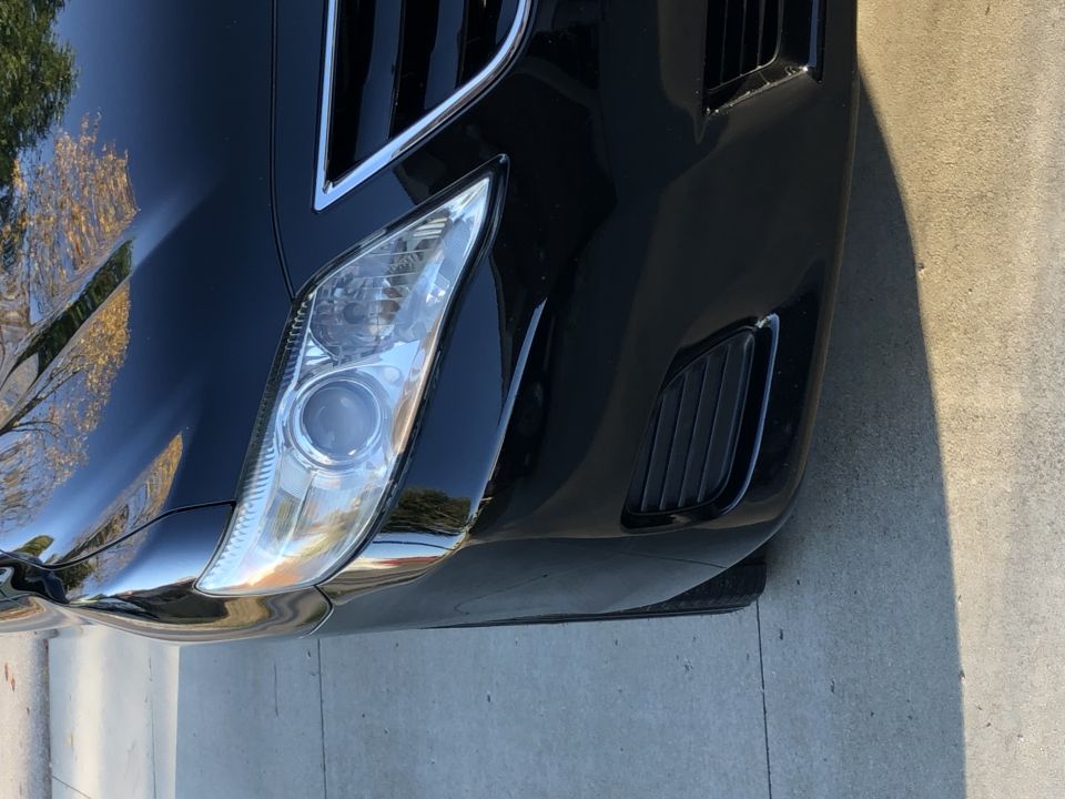 Close-up of the front bumper and headlight of a black car.