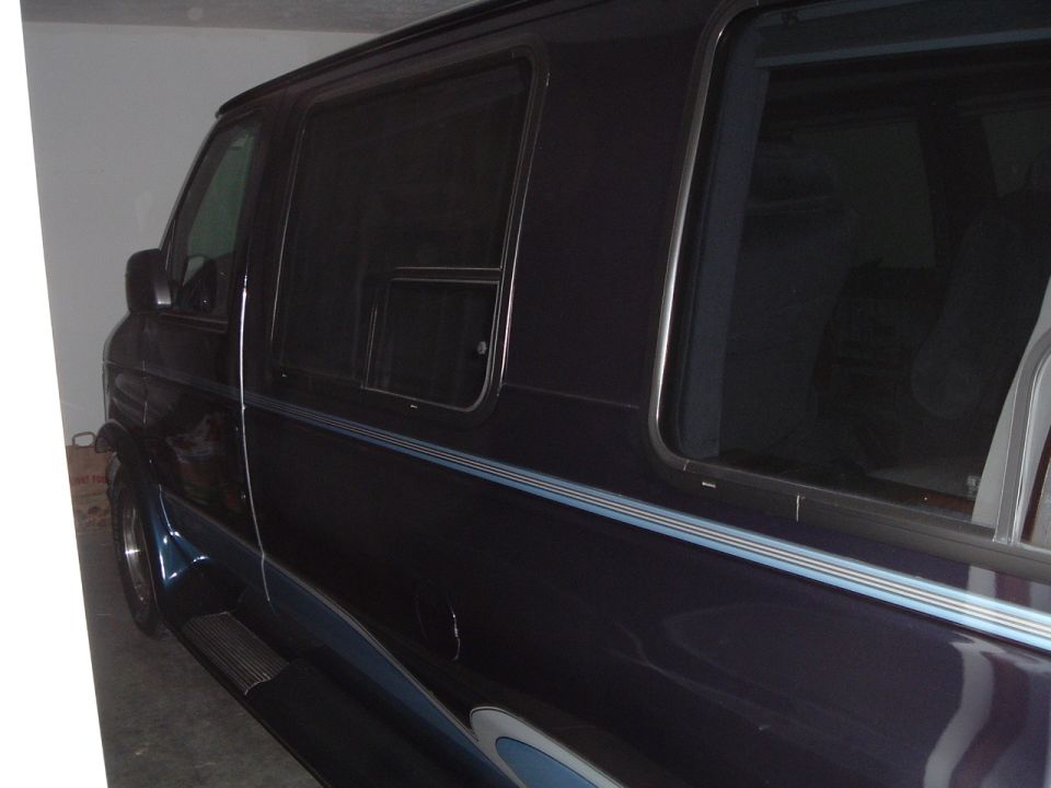 Dark blue Ford Econoline conversion van parked indoors showing side and sliding window
