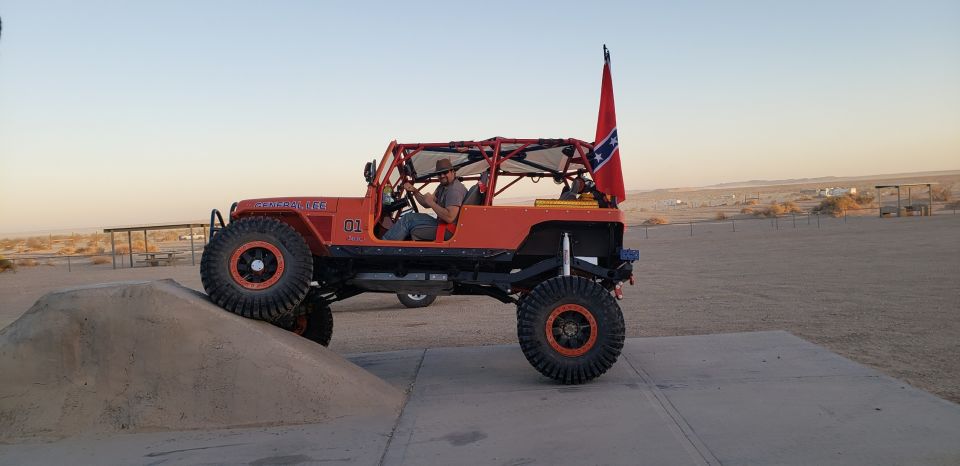 Orange Jeep Wrangler "General Lee" with Confederate flag on a dirt ramp.
