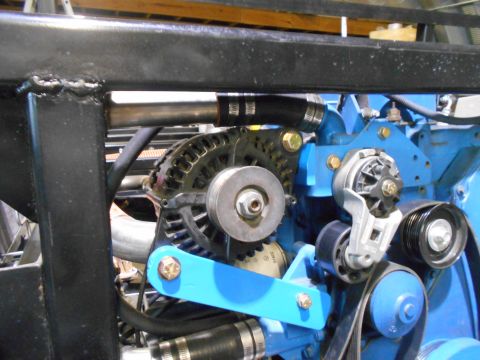 1992 Ford Bronco - A close-up view of the engine bay shows a blue engine block with an alternator and various pulleys and belts. A black metal frame is visibl…