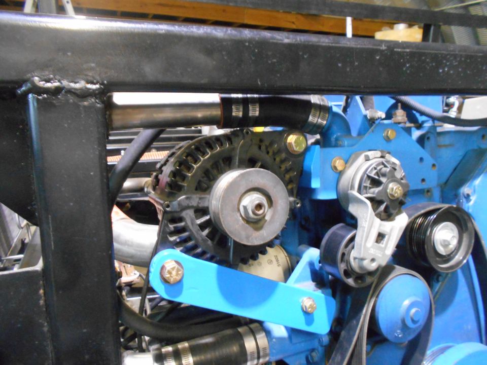 Close-up of engine bay with alternator, pulleys, belts, and blue engine block.
