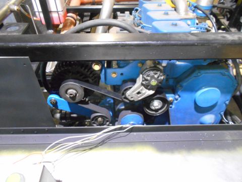 1992 Ford Bronco - A close-up view of a blue engine with a serpentine belt system and an alternator. The engine is mounted in a vehicle, with various hoses an…