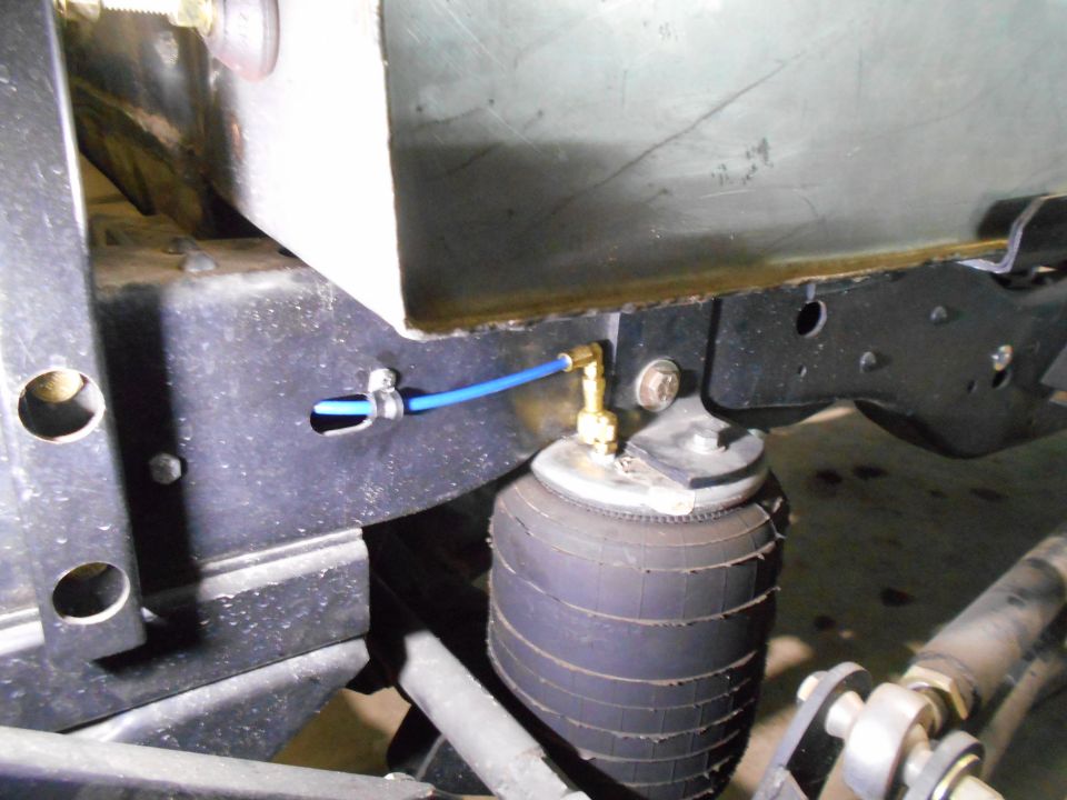 Close-up of air suspension bag and blue air line on vehicle frame.