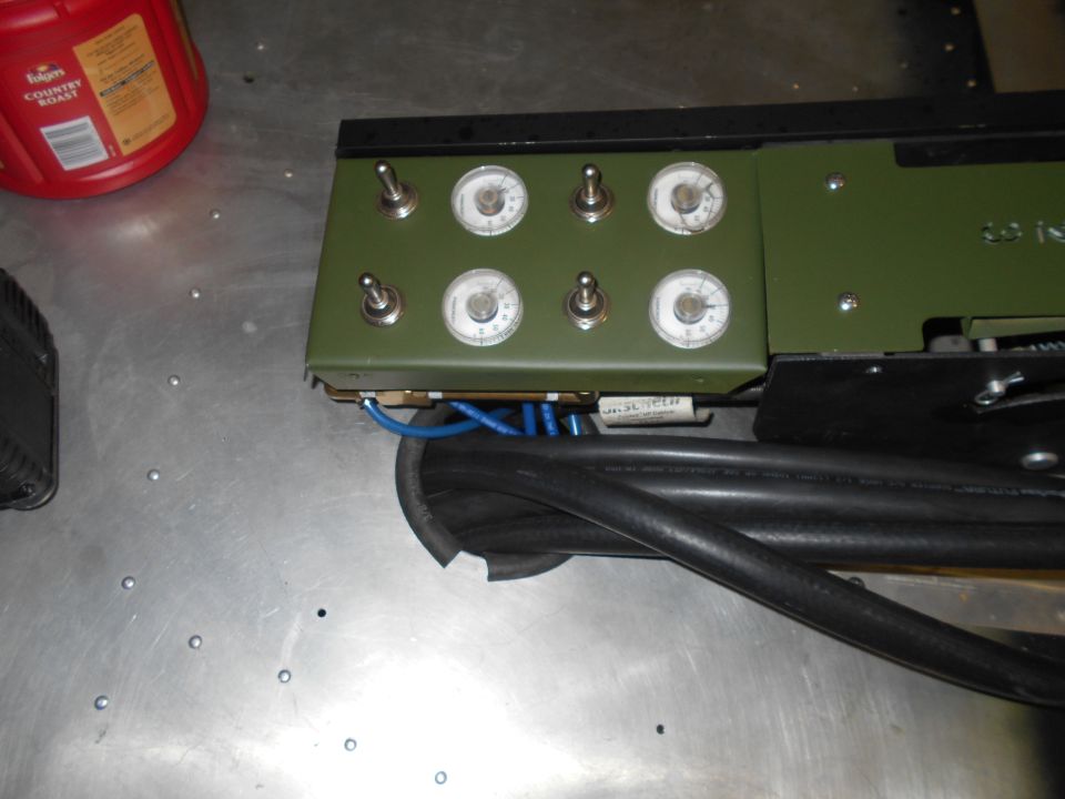 Control panel with toggle switches and gauges, connected to cables.