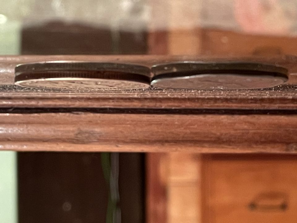 Two silver coins on a wooden surface.