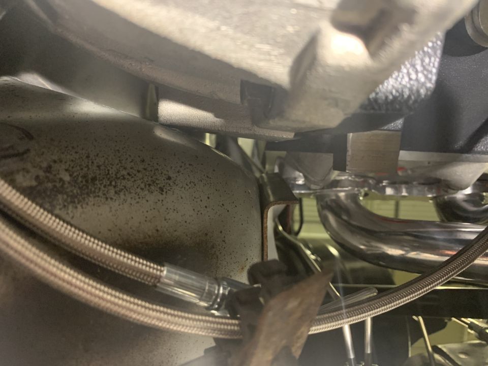 Close-up of exhaust manifold and braided brake line under a vehicle