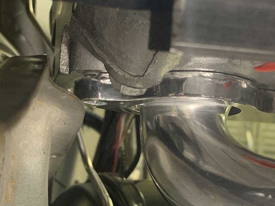 Chrome exhaust pipe connected to a cracked metal manifold