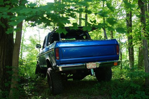 1979 Ford Bronco - 1979 Ford Bronco off-road in a wooded area, showing its rear and side profile.
