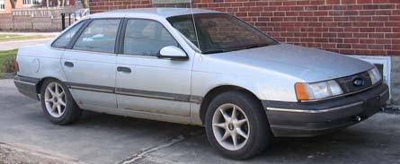 1990 Ford Taurus - Silver 1990 Ford Taurus sedan parked on a concrete driveway.