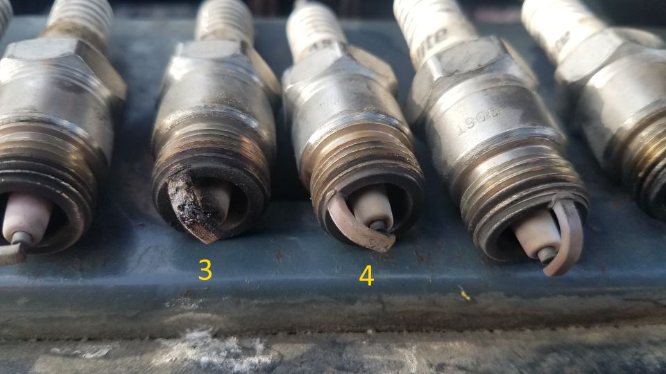 Spark plugs, one with heavy carbon buildup, labeled 3 and 4