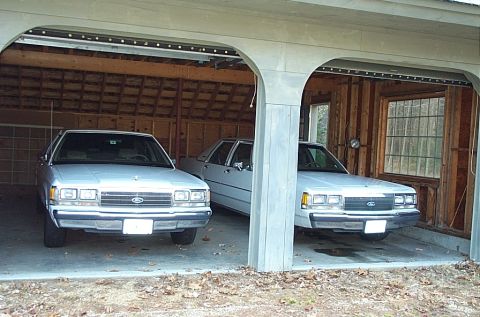 1991 Ford Crown Victoria LTD - Two white 1991 Ford Crown Victorias are parked side-by-side in a garage.
