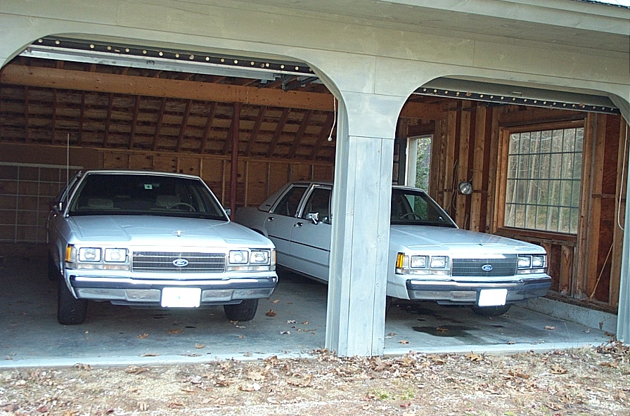 Front view of two white 1991 Ford Crown Victorias in a garage