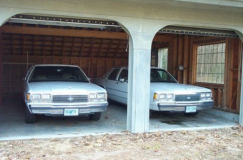 1991 Ford Crown Victoria LTD - Two 1991 Ford Crown Victoria LTD sedans are parked inside a garage.