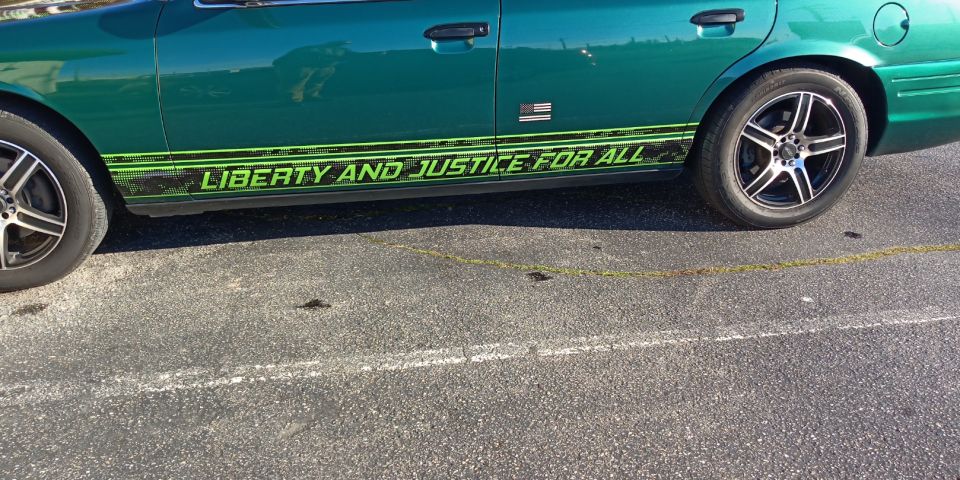 Green sedan side view with lime graphic reading 'Liberty and Justice for All' and American flag decal