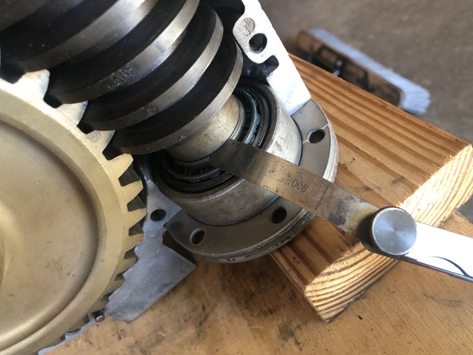 Worm gear and bearing assembly being measured with a .008 feeler gauge, supported by wooden blocks