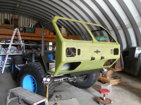 1992 Ford Bronco - This custom off-road vehicle chassis, large tires and blue rims, is in a workshop undergoing construction.