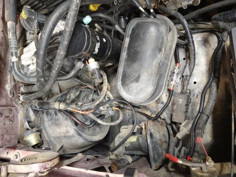 1996 Ford Bronco - Close-up view of the engine bay, showing various hoses, wiring, and the air intake assembly.