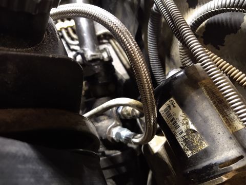 1996 Ford Bronco - Engine bay detail showing a braided hose and a Ford-labeled component.