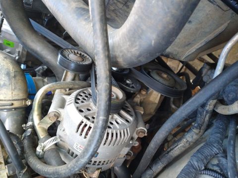 1996 Ford Bronco - The engine bay of a vehicle, focusing on the alternator and serpentine belt system.