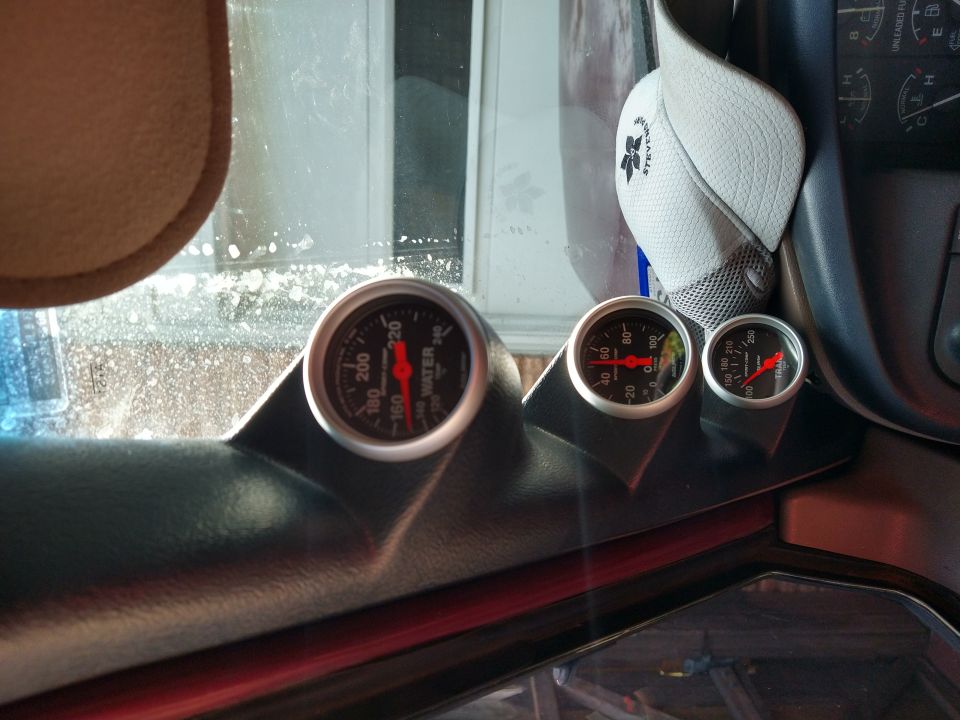 Dashboard with three gauges: water temperature, oil pressure, and voltmeter. A white baseball cap is on the dashboard