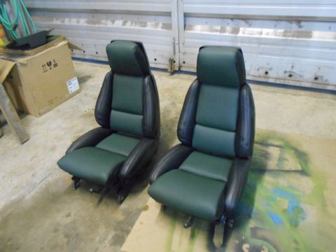 1992 Ford Bronco - Two car seats, upholstered in green and black, sit on a concrete floor.