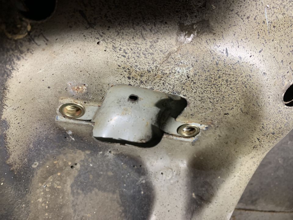 Close-up of a metal bracket with two bolts on a vehicle's undercarriage