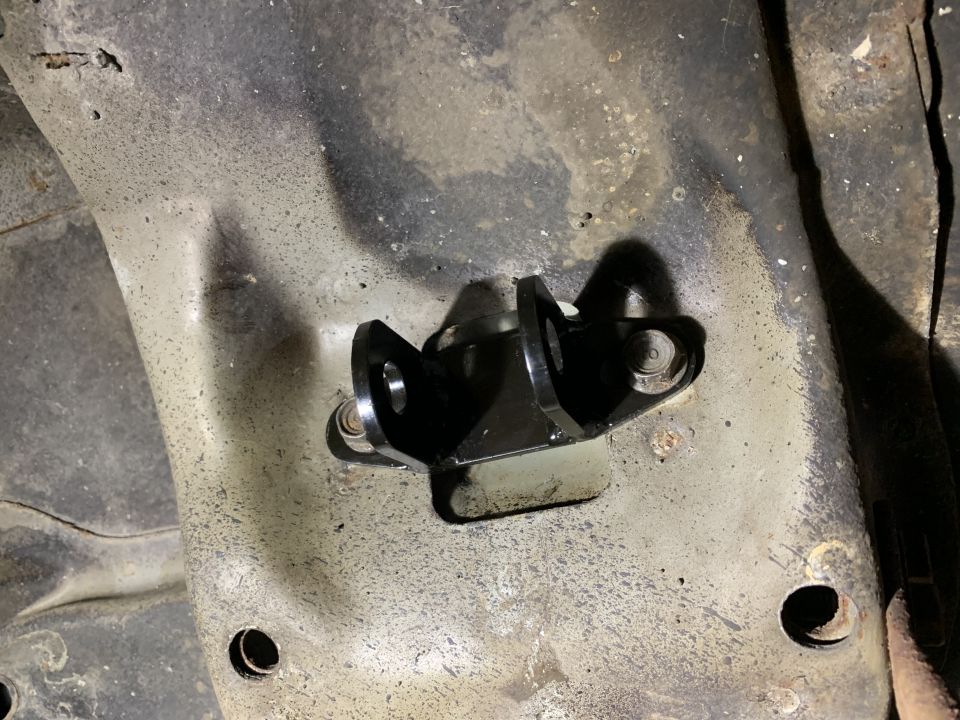 Close-up of a black bracket bolted to a vehicle's undercarriage frame