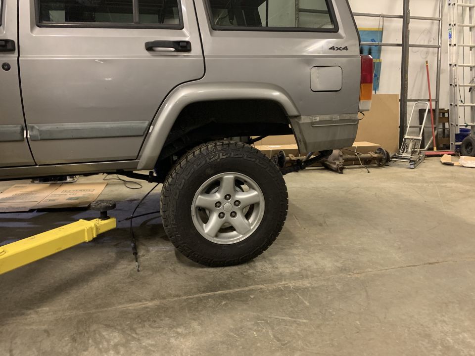 Silver 2000 Jeep Cherokee side view, lifted, with rear axle removed