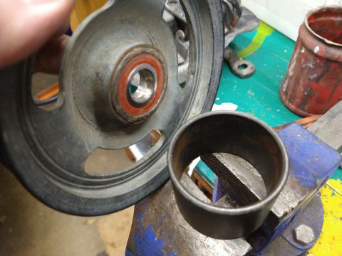 1996 Ford Bronco - A close-up view shows a metal pulley with a bearing and a metal sleeve clamped in a vise. The pulley appears to be part of a vehicle's engi…
