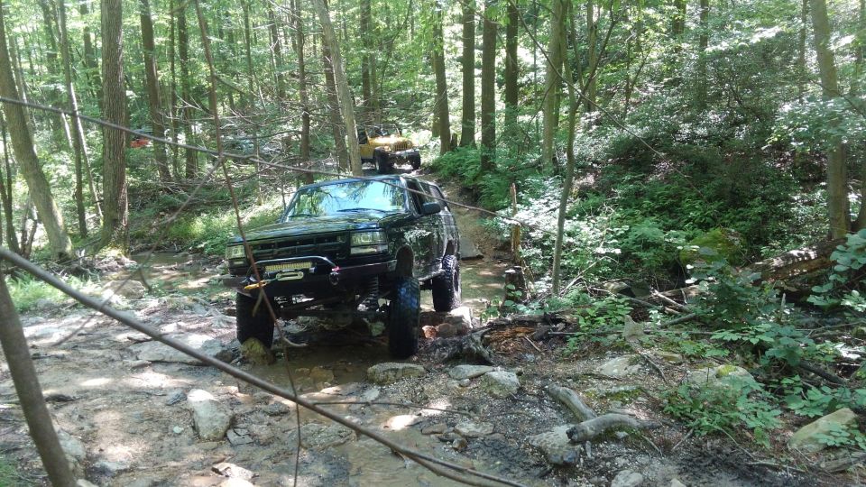 Black Ford Bronco off-roading on a rocky, wooded trail.