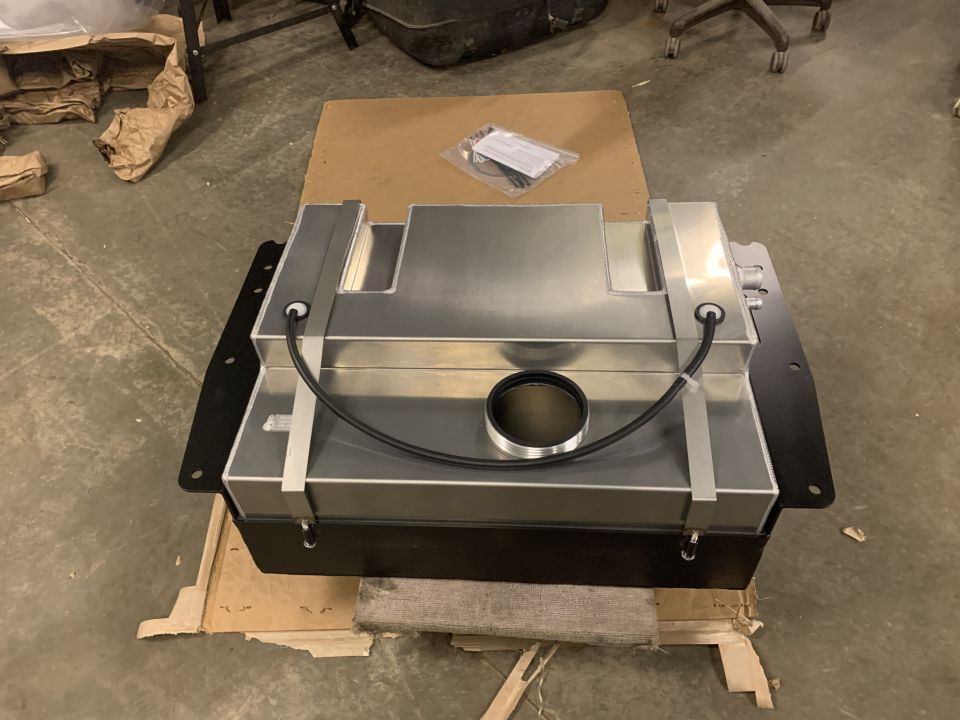 Custom aluminum fuel tank assembly on a black bracket.