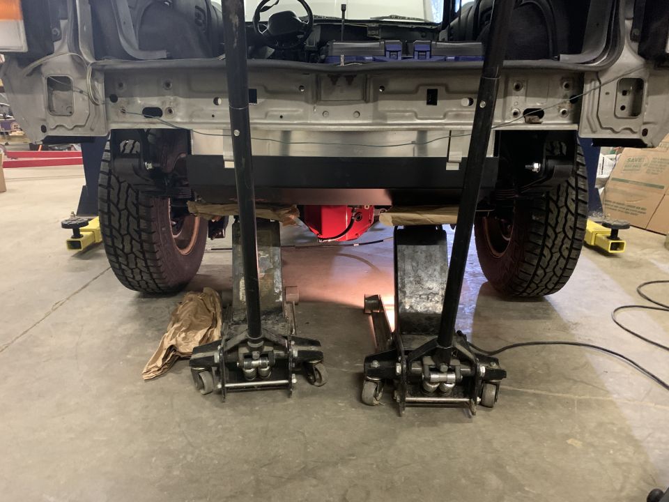 Rear view of a Jeep Cherokee on floor jacks with a red differential visible.
