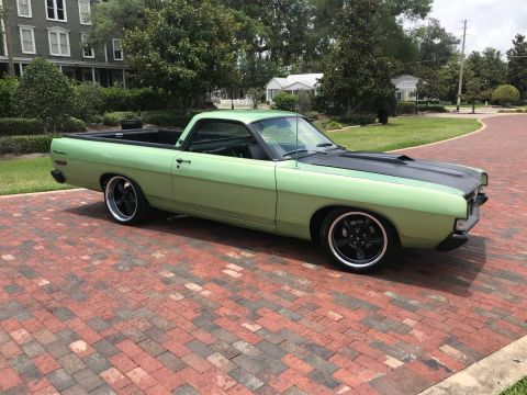 1968 Ford Ranchero - This light green 1970 Ford Ranchero features a contrasting black hood and aftermarket wheels, parked on a decorative brick driveway.